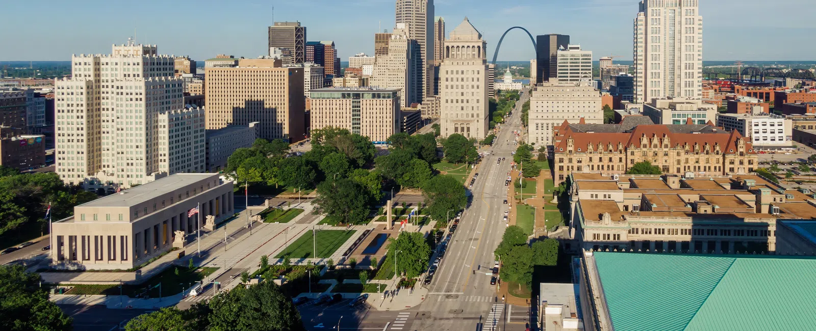 Aerial view of downtown St. Louis with prominent Gateway Arch and city skyline on a clear day.