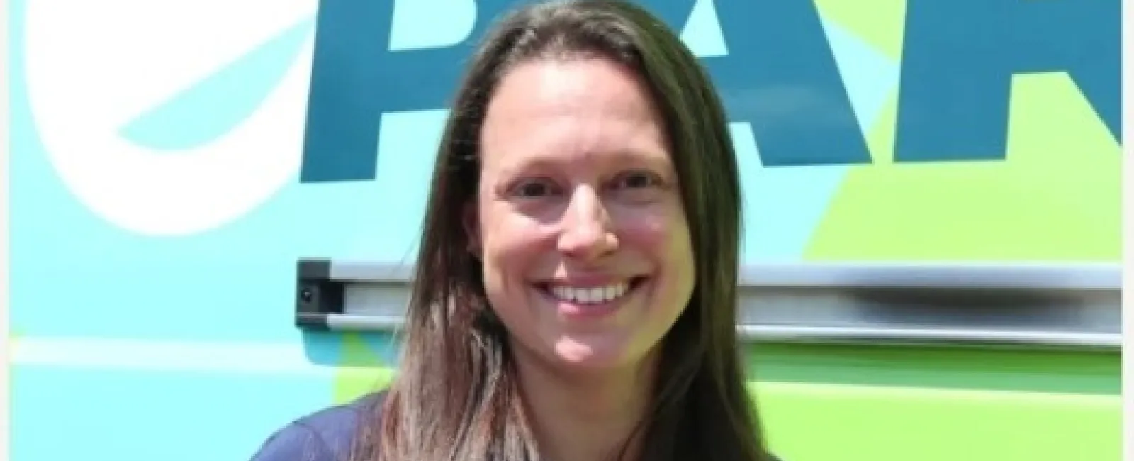 Portrait of Lizzie Sigafoos, a standout female franchise owner, smiling in front of a branded vehicle background.