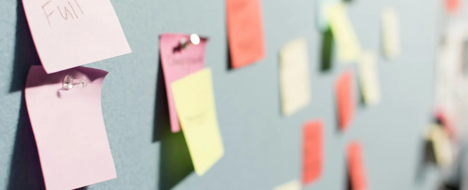 Colorful sticky notes pinned on a wall used for organizing ideas and tasks in a brainstorming session.