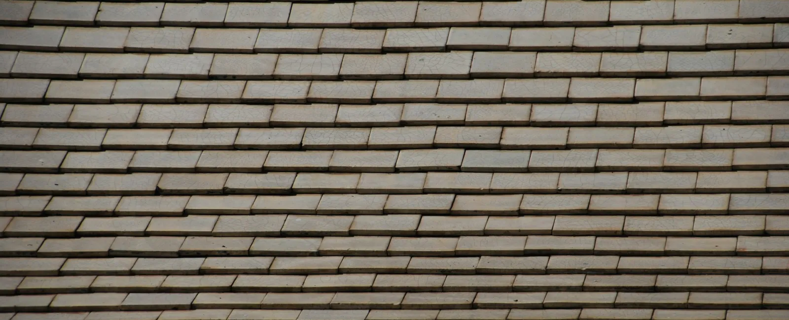 Close-up of a shingled roof with overlapping gray tiles arranged in horizontal rows.