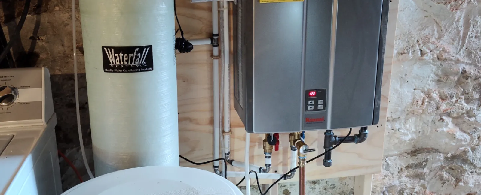 Water heater installation in basement with tank, water softener, and plumbing elements visible.