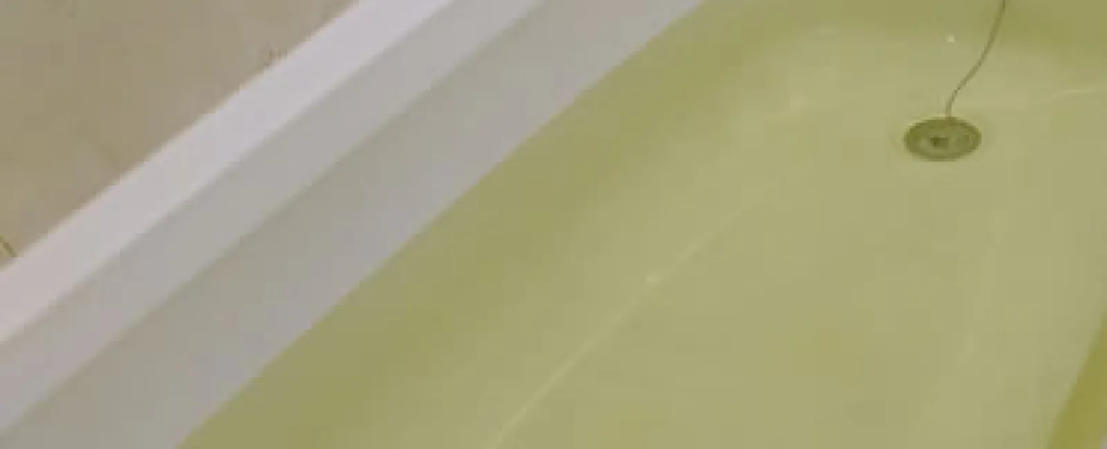 Close-up of a bathtub filled with clear water showing the drain and overflow plug chain.