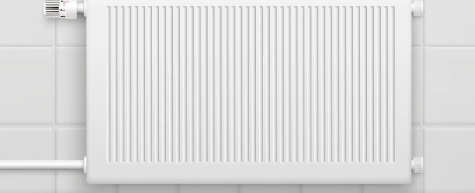 White radiator mounted on white tiled wall with adjustable thermostat valve on the left