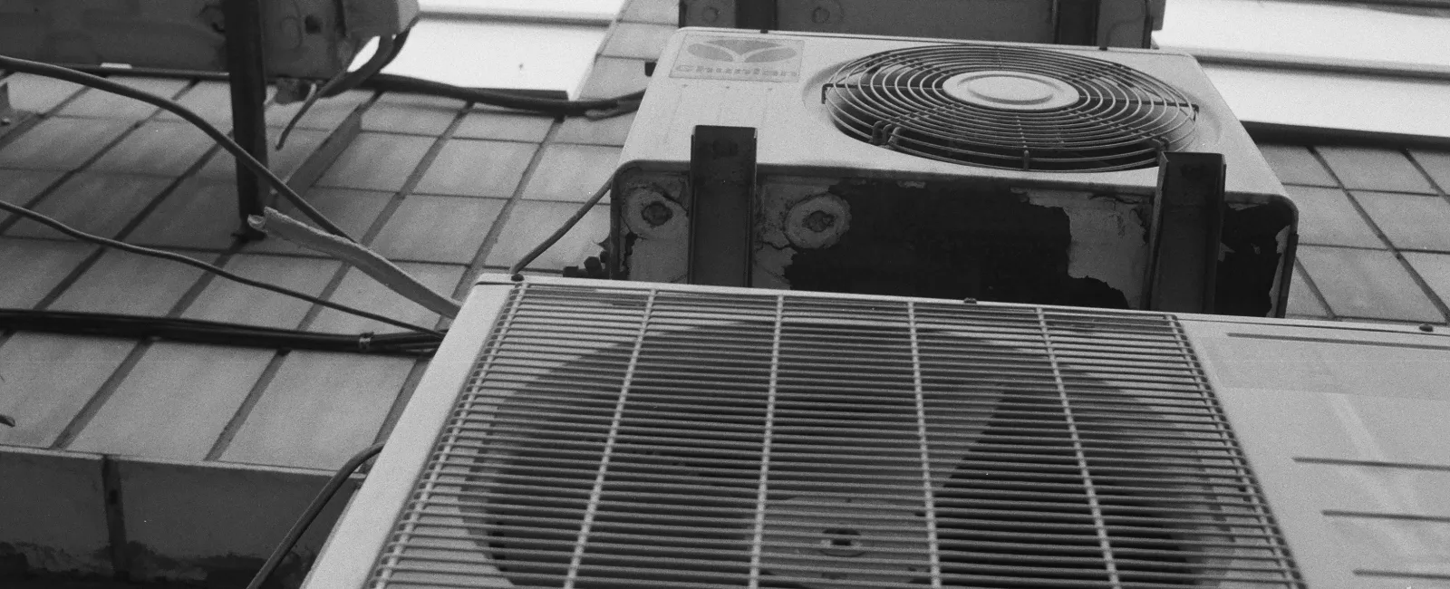 Multiple outdoor air conditioning units mounted on a building wall in a vertical arrangement.