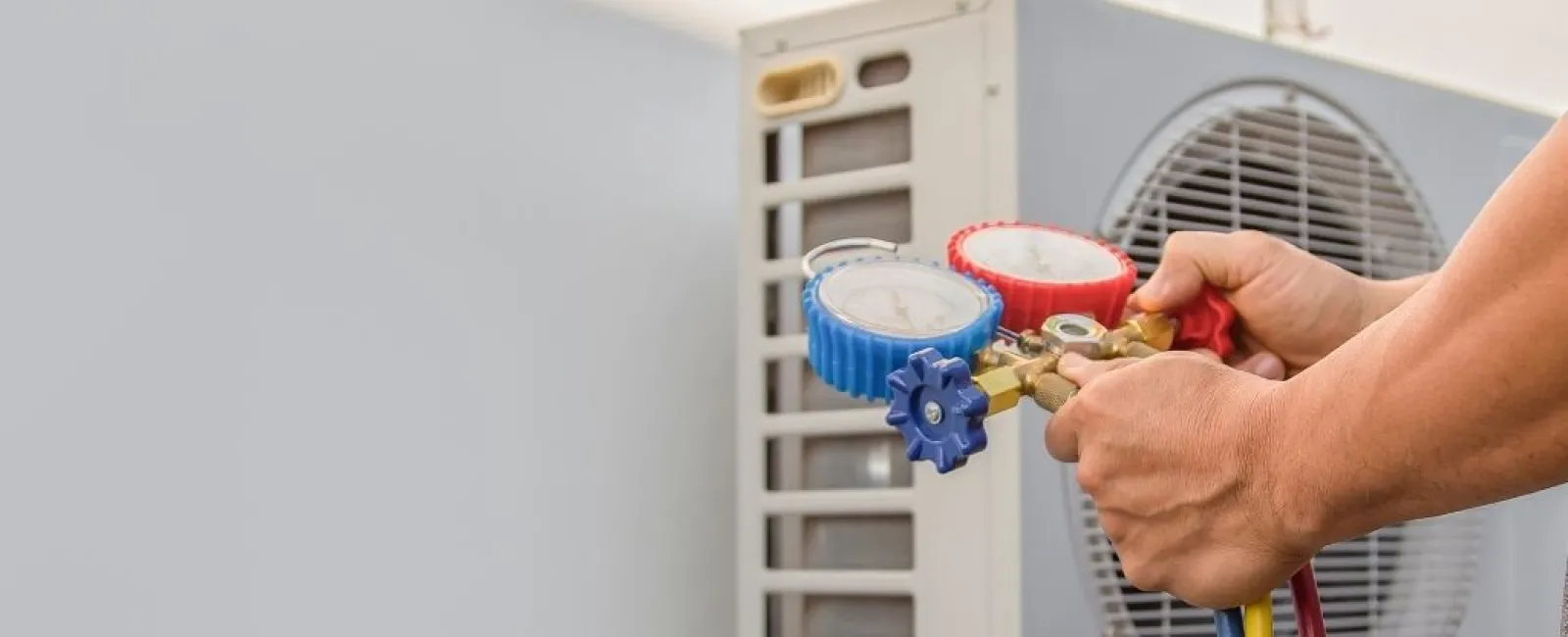 Technician using pressure gauges to check and service an outdoor air conditioning unit's HVAC system.