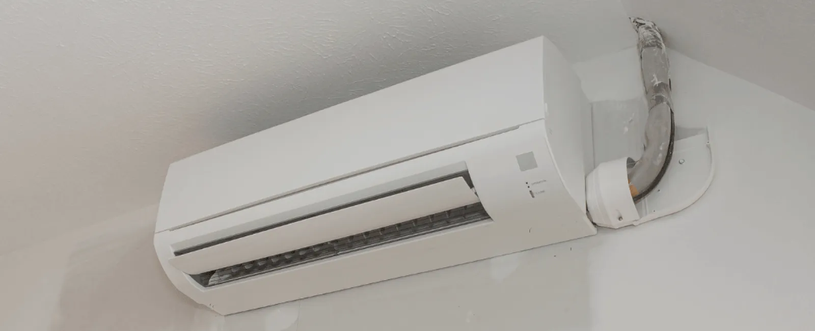 Wall-mounted white air conditioning unit installed above a doorway in a room under renovation.