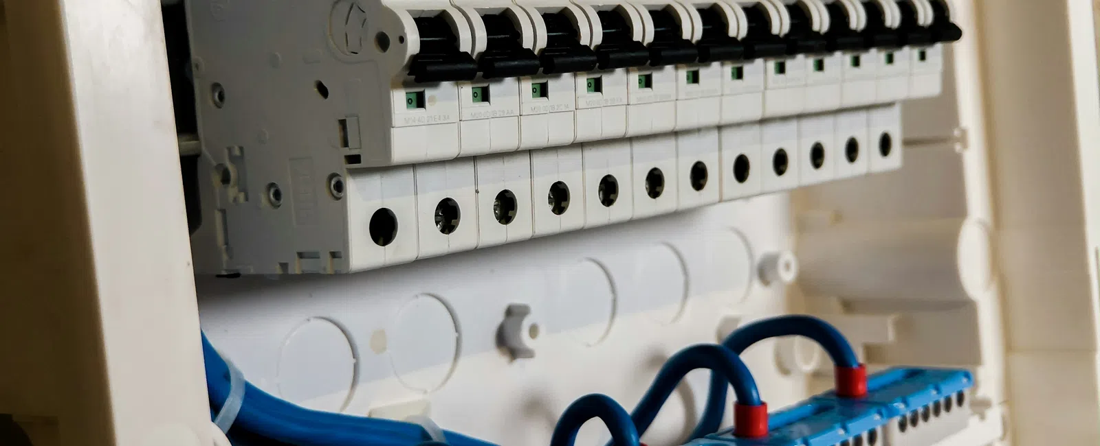 Close-up of an electrical circuit breaker panel with multiple switches and blue wiring connections.