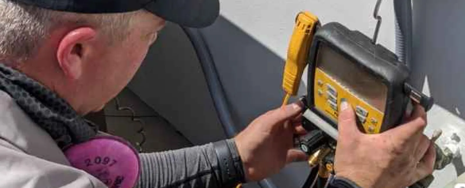 Technician adjusting HVAC system with a digital manifold gauge for maintenance and pressure measurement.
