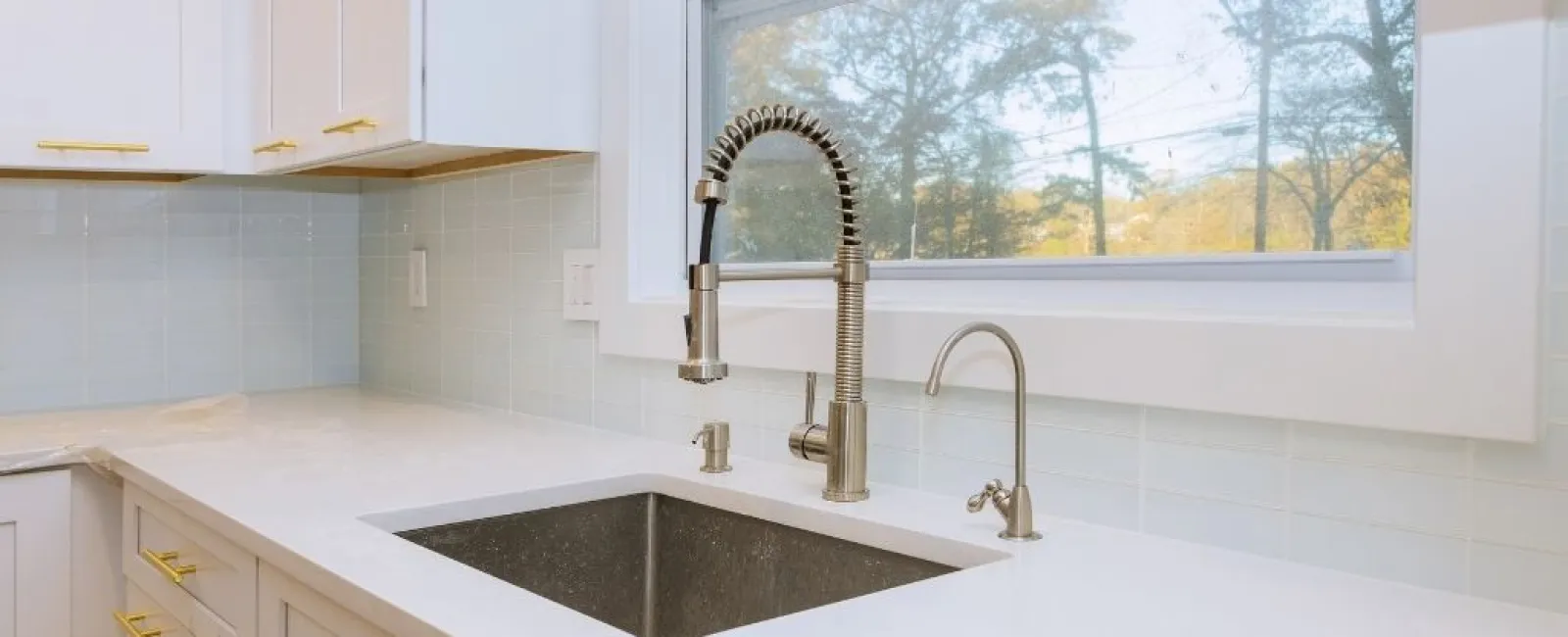 Modern kitchen countertop with stainless steel sink, spring pull-down faucet, and large window view