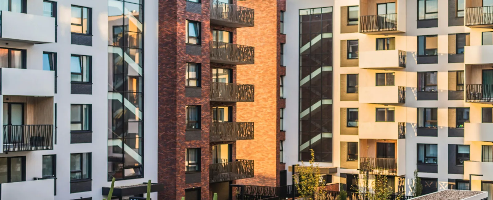 Modern apartment buildings with balconies surrounding a landscaped courtyard in soft evening light.