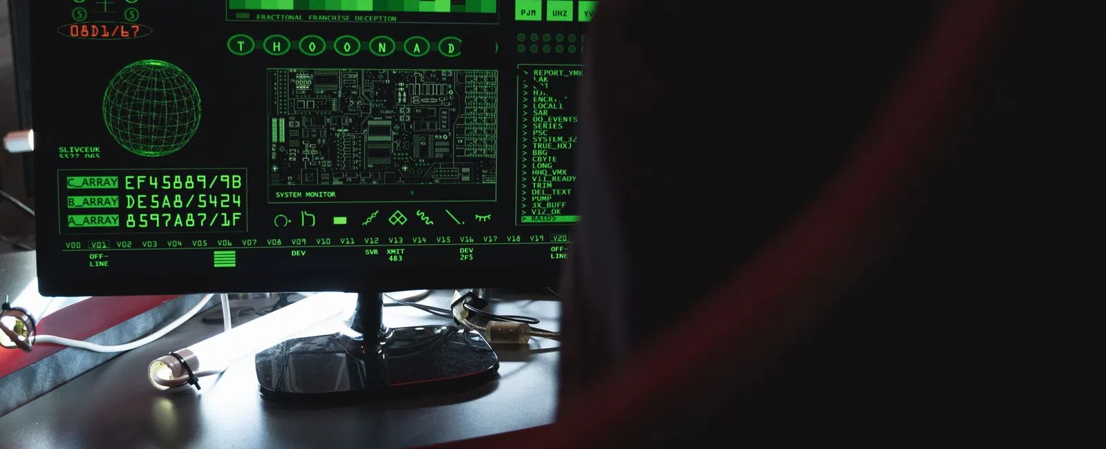 Computer screen displaying green digital data, graphs, and circuit diagrams in a dark room setting.