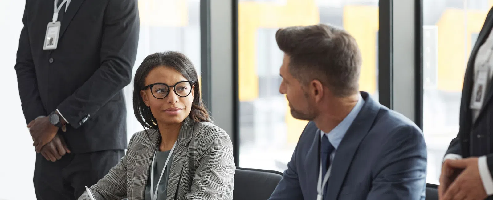 Professional businesspeople discussing and taking notes during a meeting in a modern office conference room.