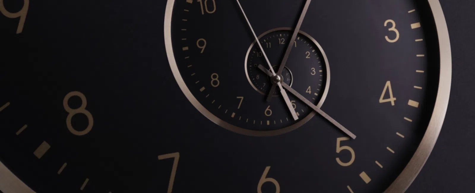 Close-up of a black spiral clock with gold numbers and clock hands showing time in a repeating pattern.