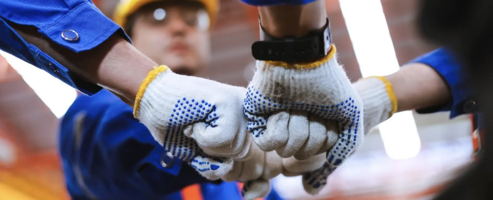Construction workers in safety gear joining fists in team unity symbol on site