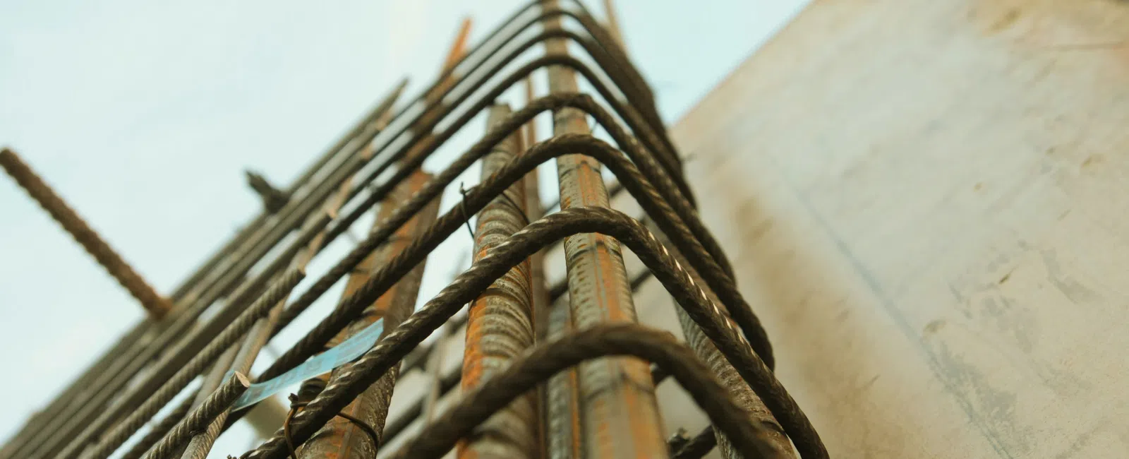 Close-up of rusted steel rebar grid for concrete reinforcement at a construction site with sky background.