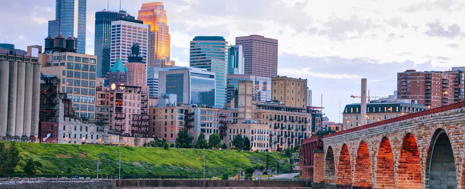Minneapolis skyline with historic stone arch bridge over the Mississippi River at sunset with colorful city buildings