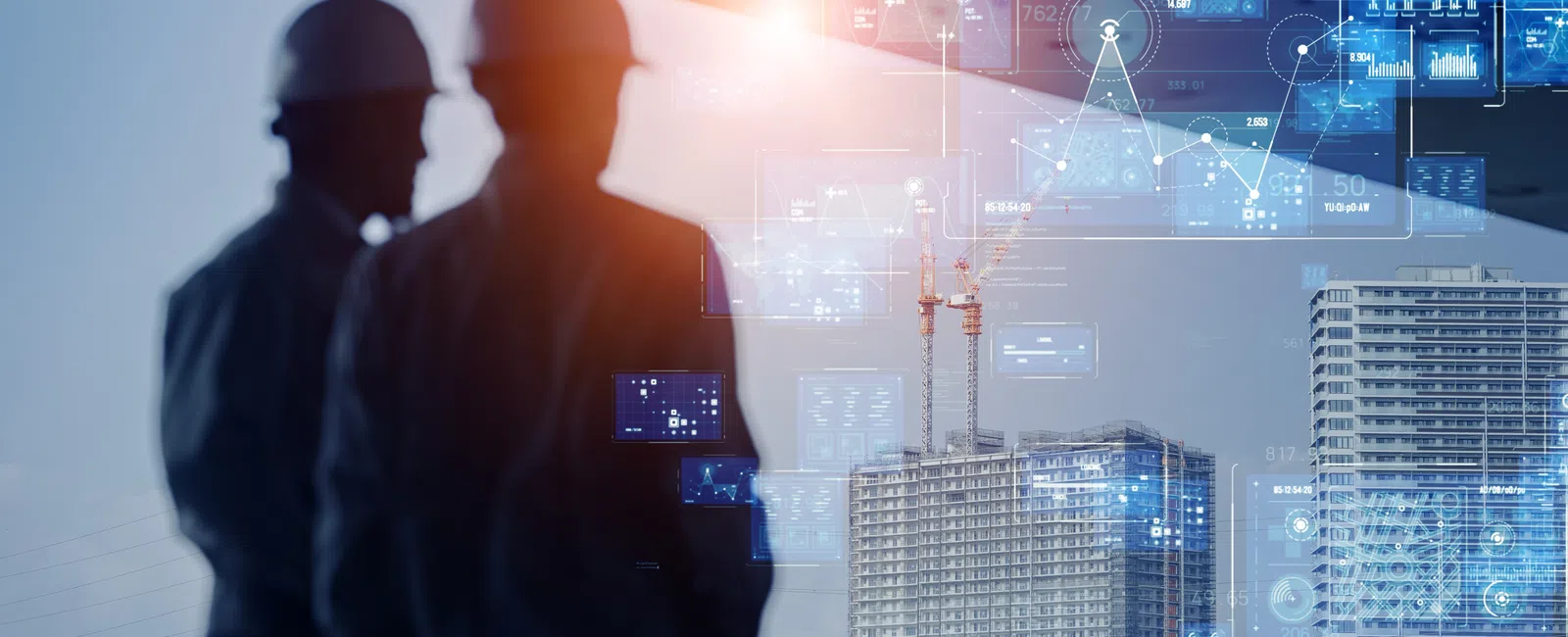 Engineers in safety helmets analyzing digital data over a construction site with high-rise buildings at sunset.