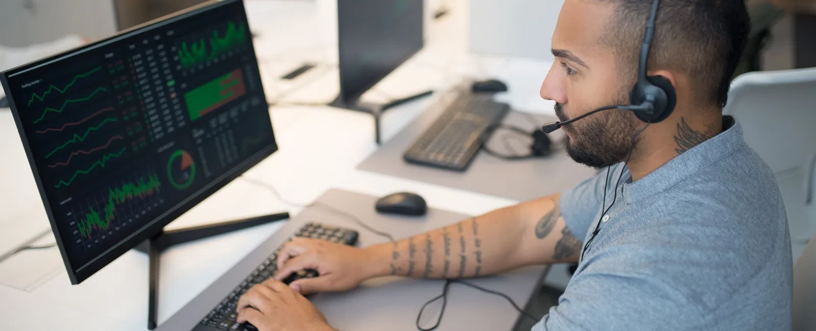 Man with headset working on data analysis at computer in modern office environment