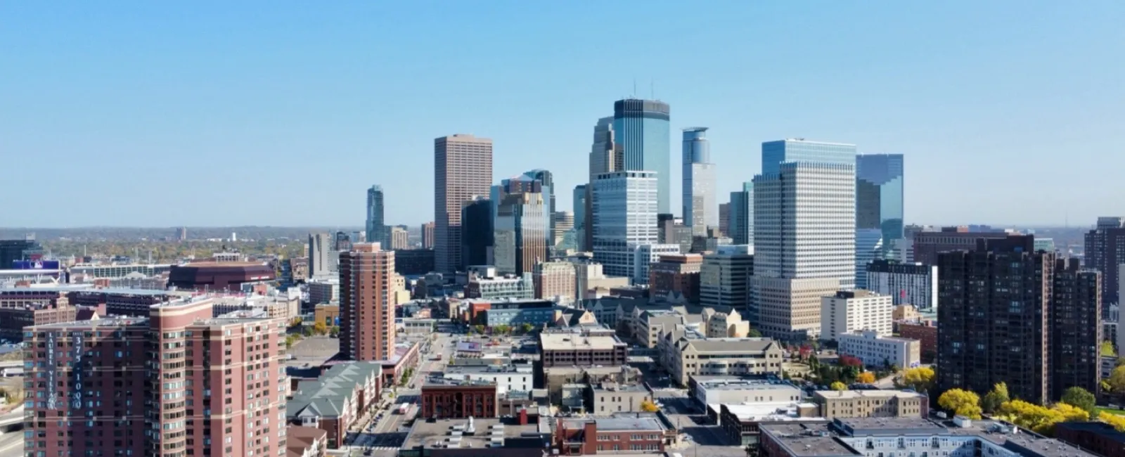 Aerial view of a city skyline with modern skyscrapers under a clear blue sky on a sunny day