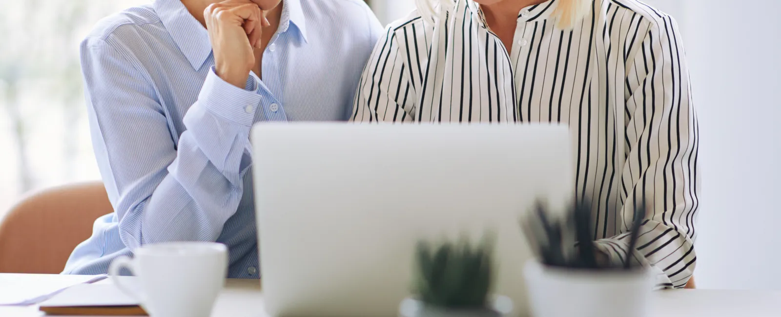 a woman and a man sitting at a table with a laptop