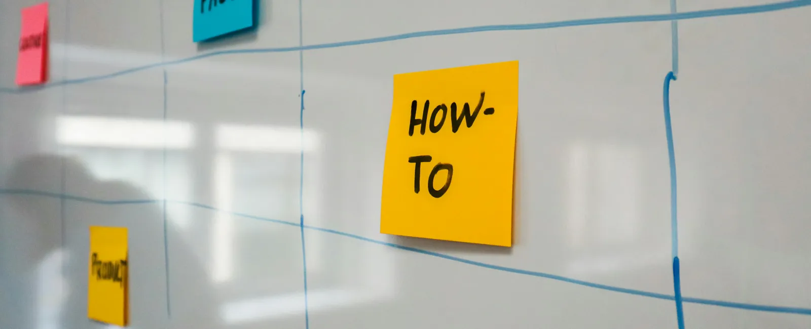 Sticky notes with words like HOW-TO and FUN FACT on a whiteboard with blue grid lines
