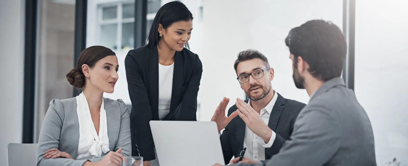 Business team collaborating during a meeting with laptop and documents in a modern office setting.