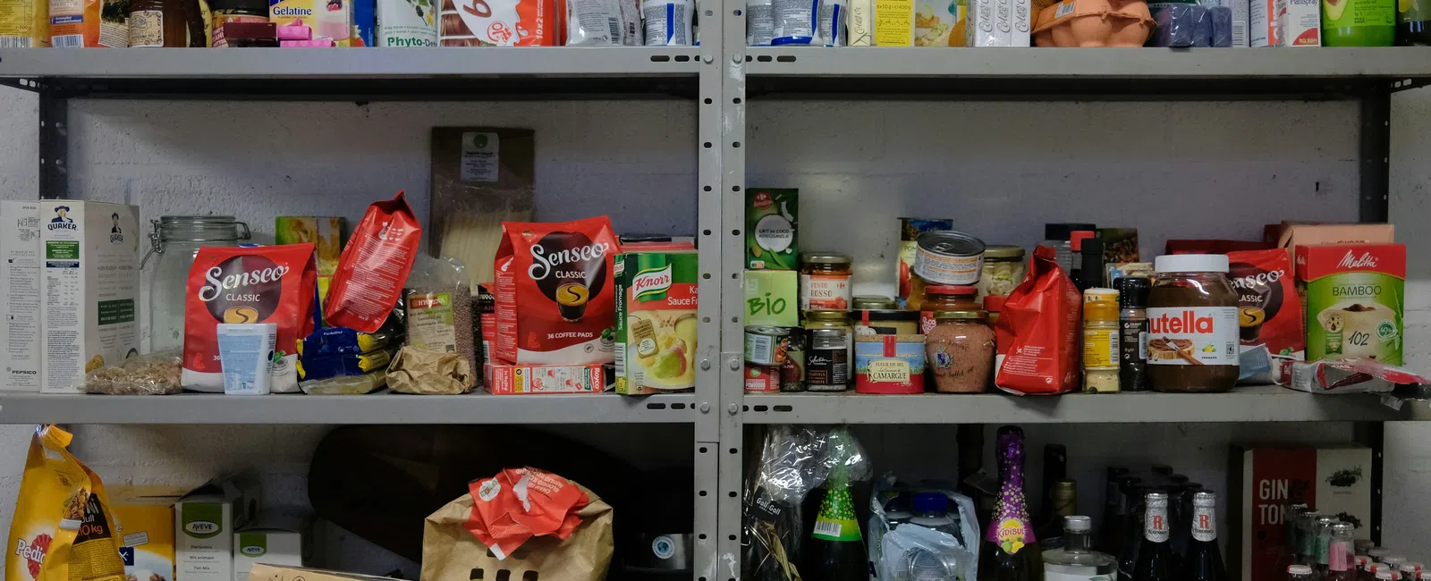 Metal shelves stocked with various food items including snacks, beverages, jars, and boxes in a storage room.