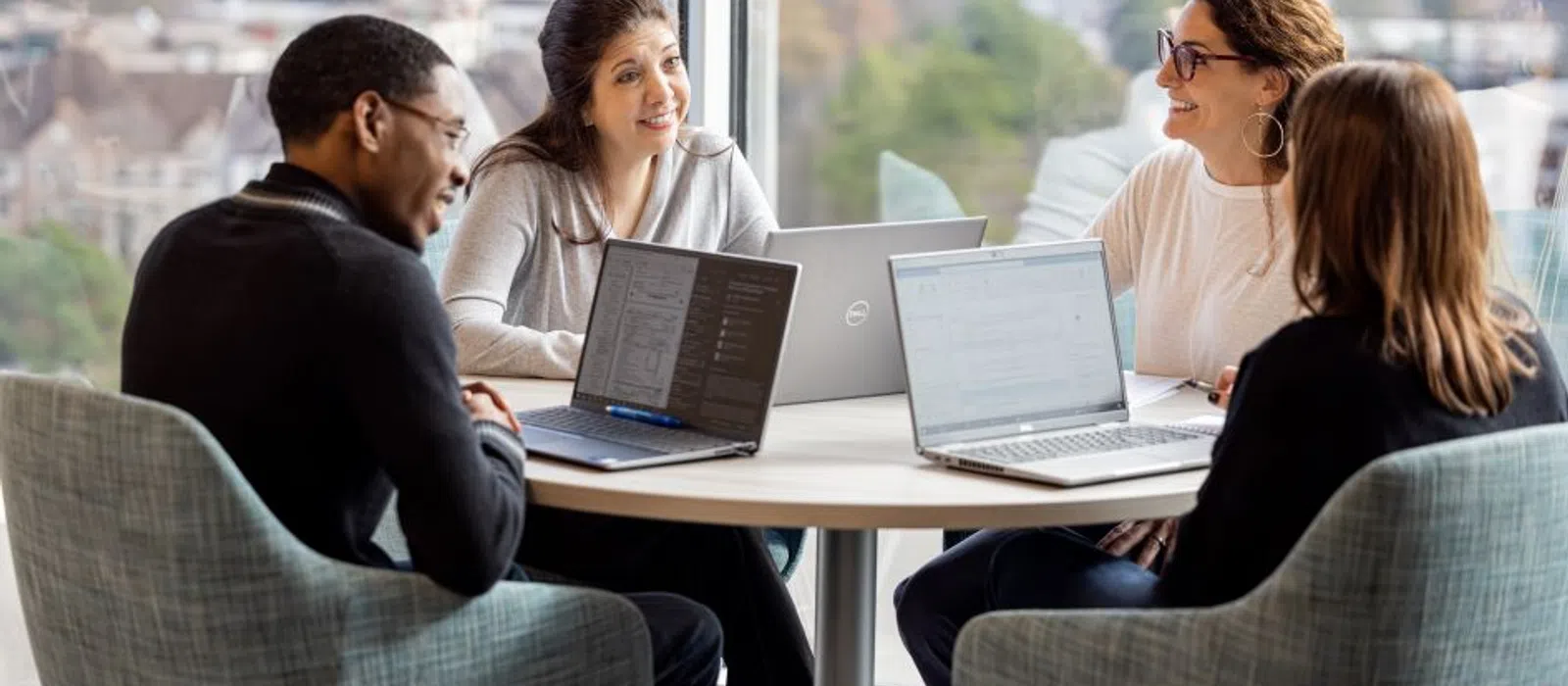 Group of professionals collaborating at a table with laptops in a modern office setting.