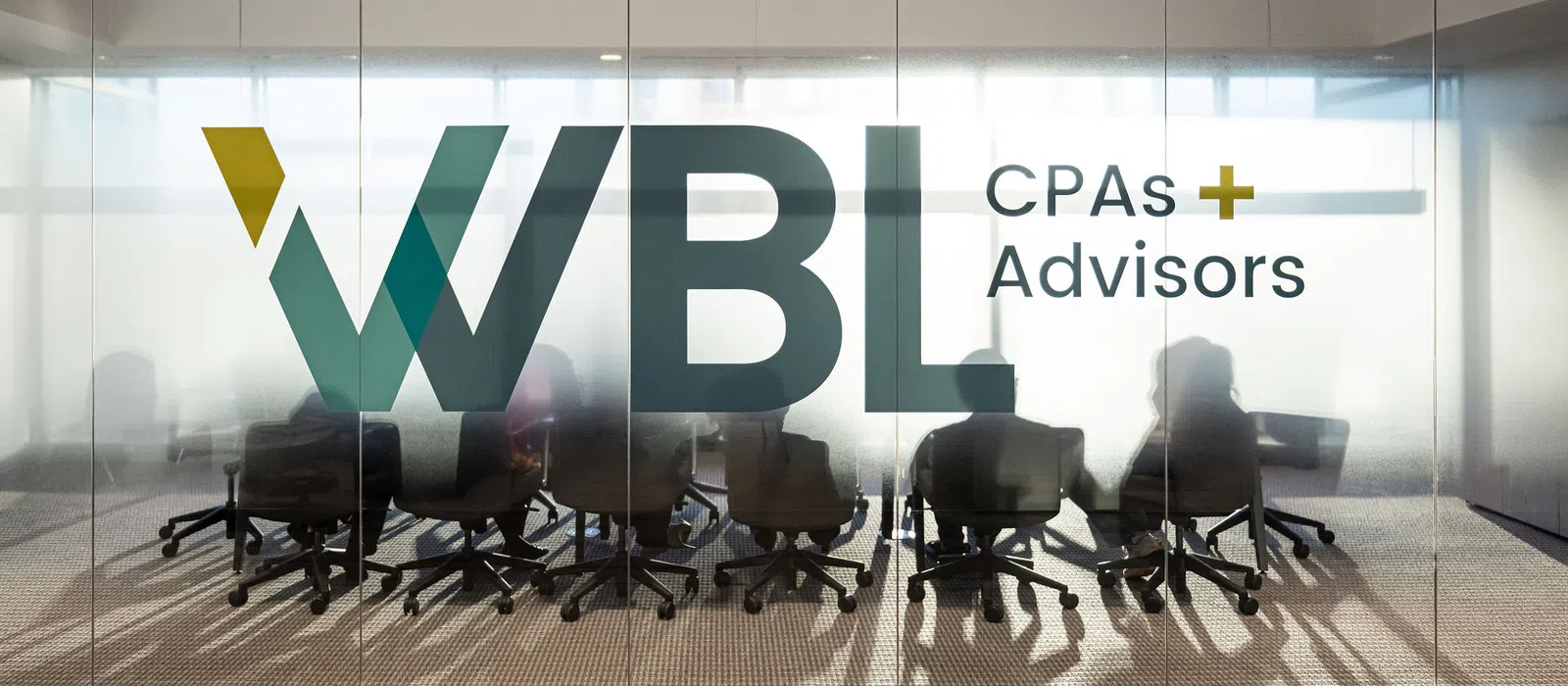WBL CPAs Advisors logo on glass wall with silhouettes of people in a meeting room behind it.