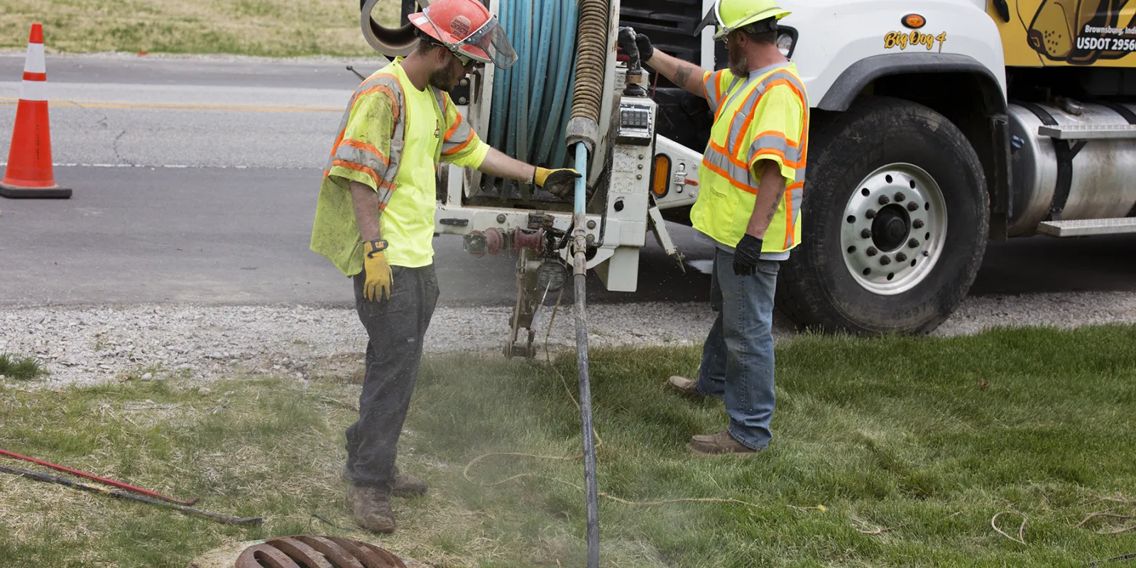 Two professionals performing sub-surface utility engineering with truck