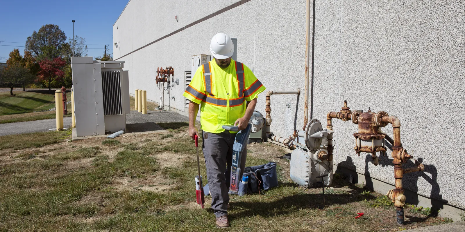 Man carrying equipment to locate private utilities underground