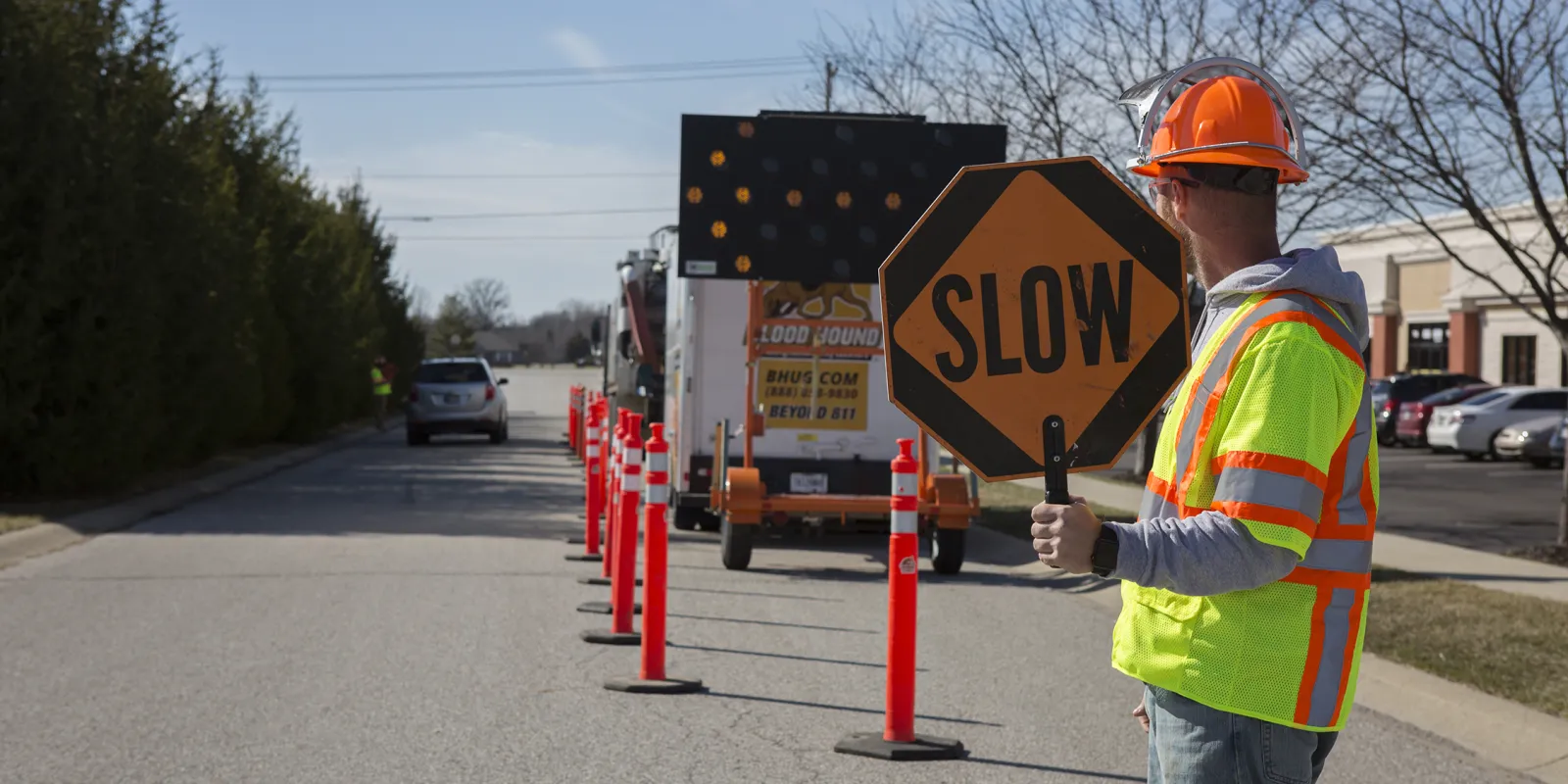 Man in construction gear holding a slow sign to manage traffic safety