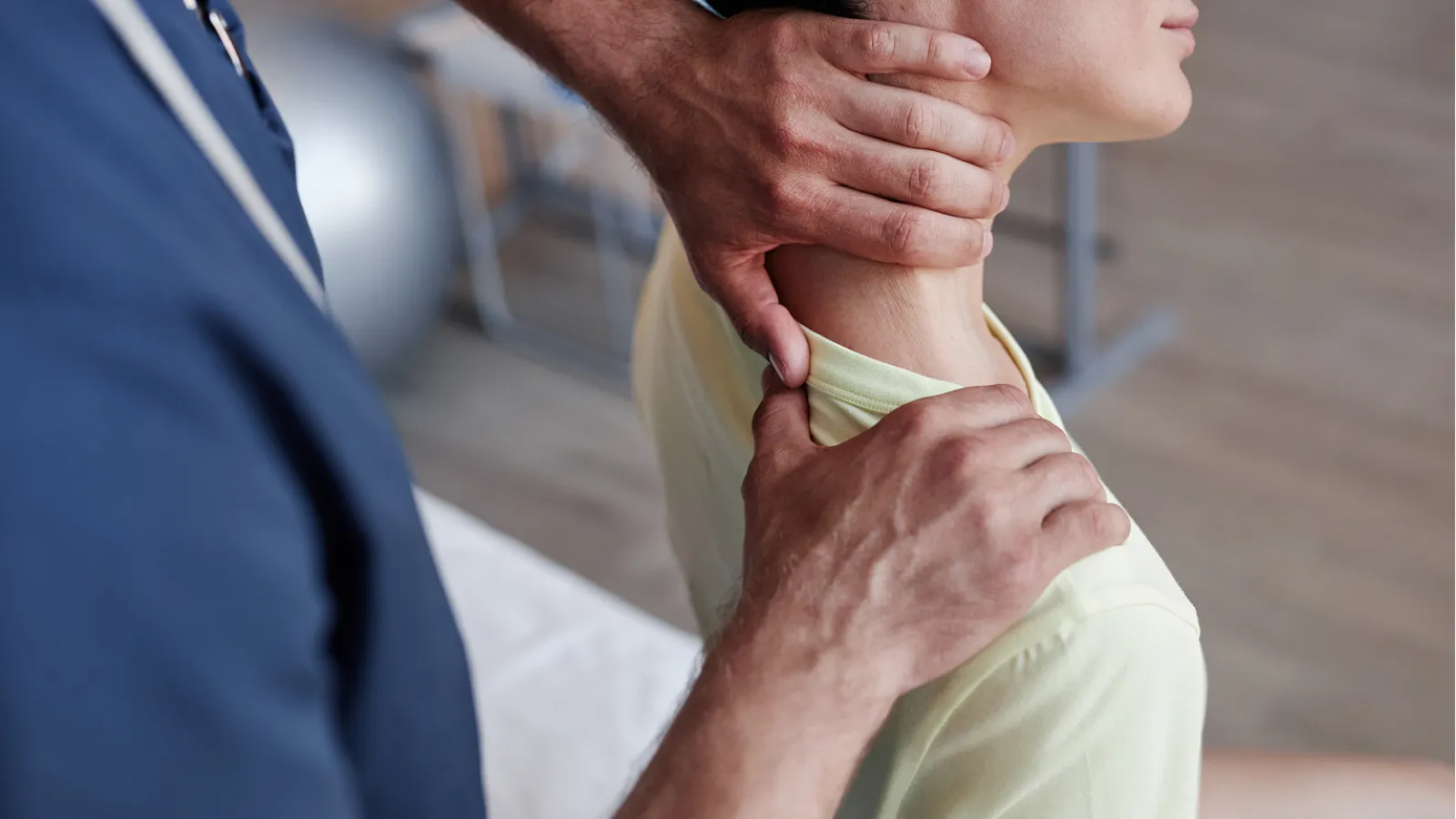 Chiropractor adjusting a woman's neck and shoulder during a therapy session indoors.