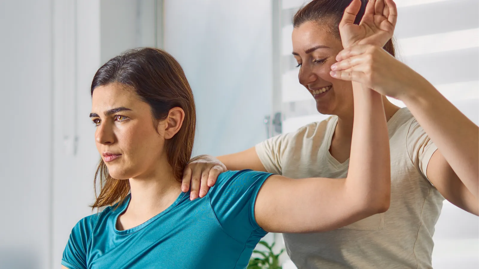Chiropractor adjusting female patient seated on treatment table in modern clinic setting