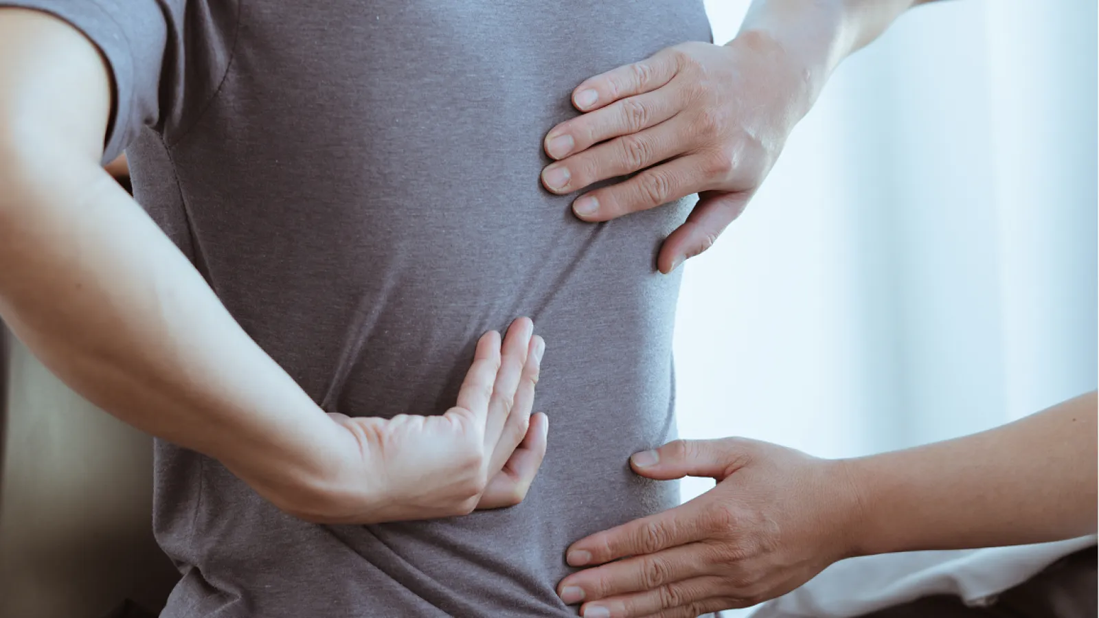 Physical therapist assisting man with lower back pain pain relief exercises during treatment session