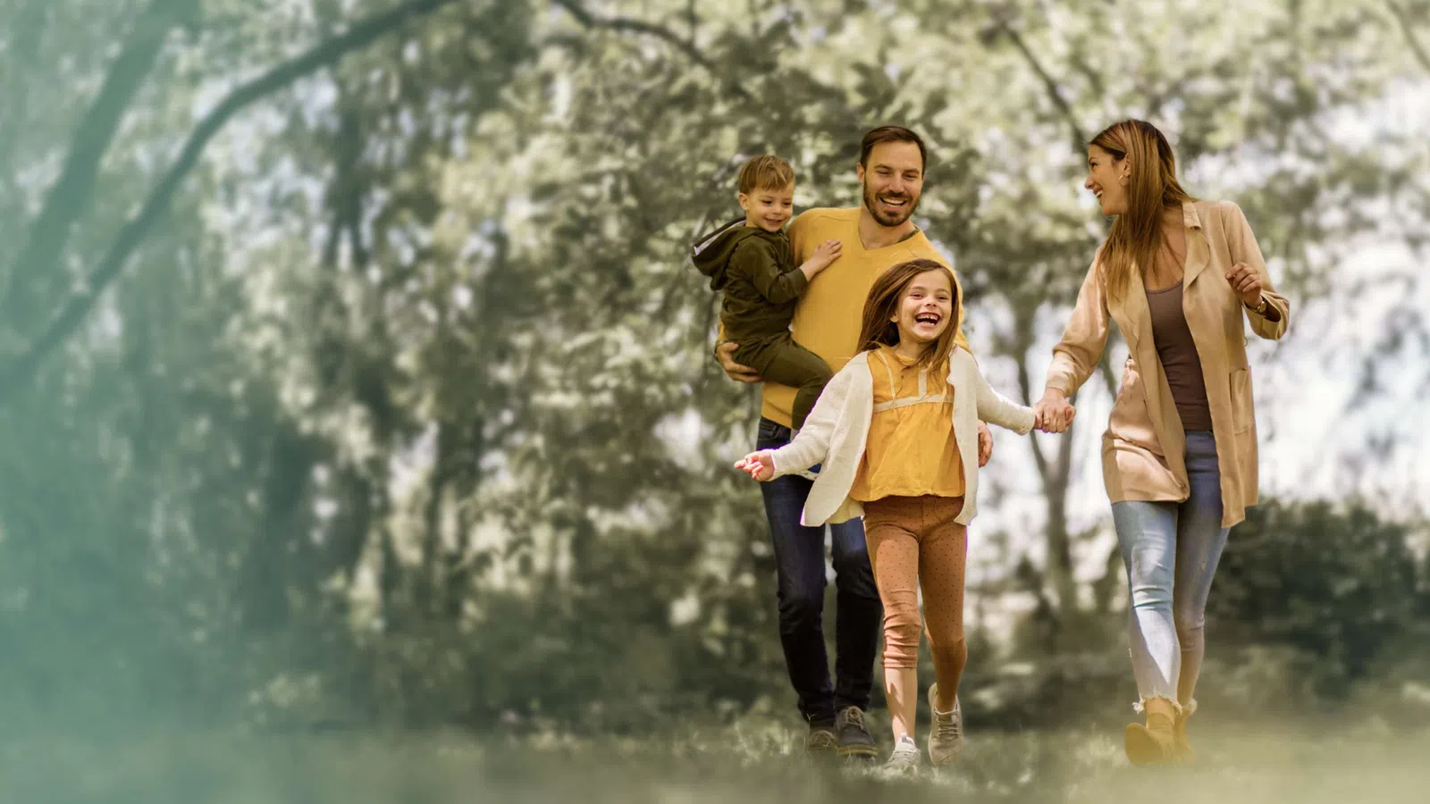 Happy family of four walking outdoors in autumn with children, parents holding hands and smiling