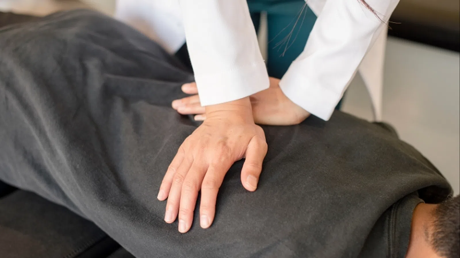 Therapist performing hands-on chiropractic adjustment on patient's back in a clinic setting