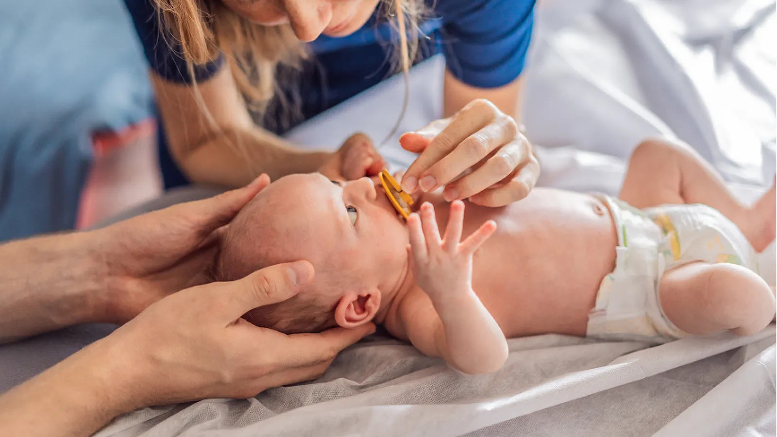 Parent gently giving pacifier to newborn baby lying on changing table with loving care