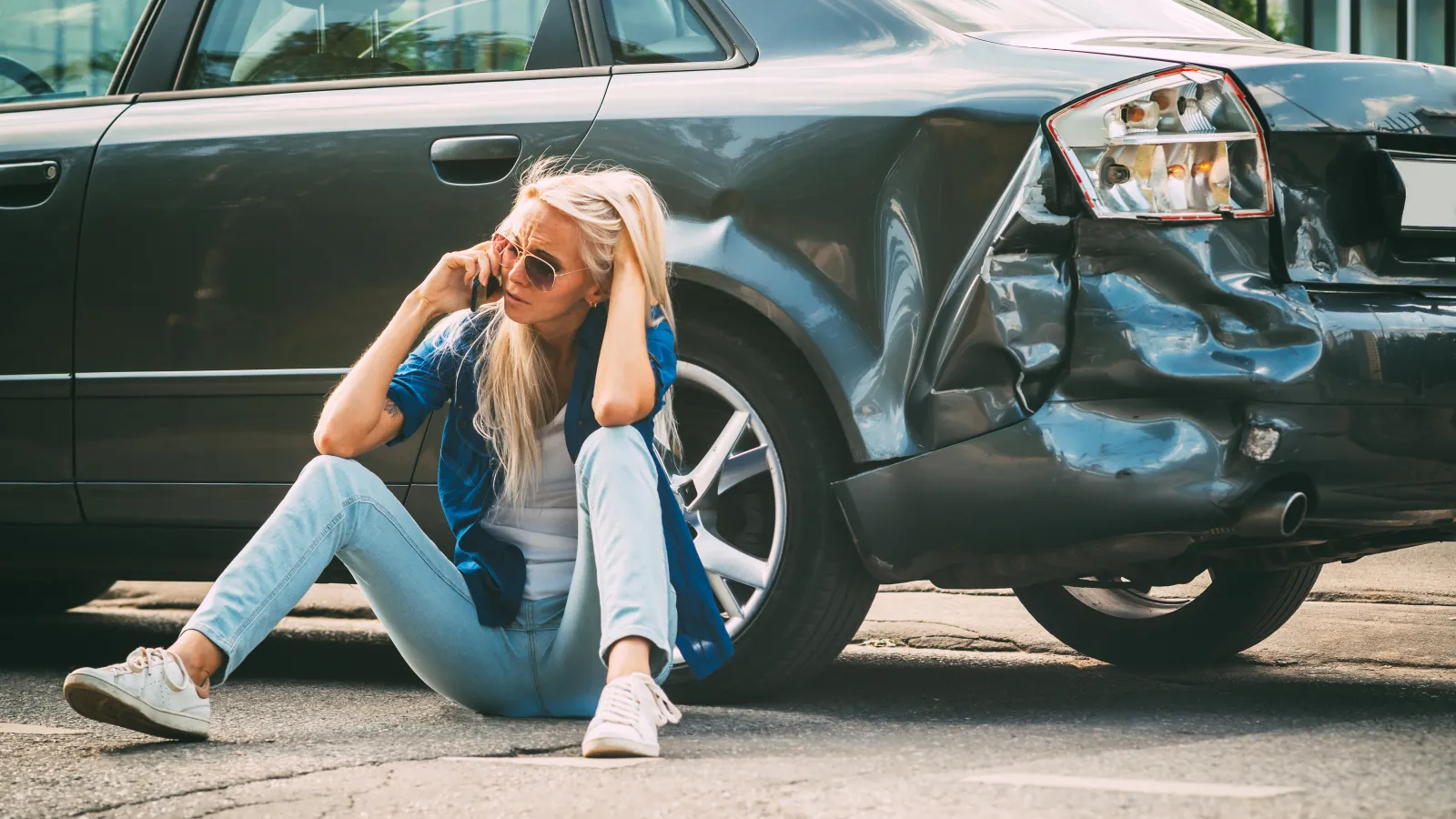 a person sitting on the ground next to a car