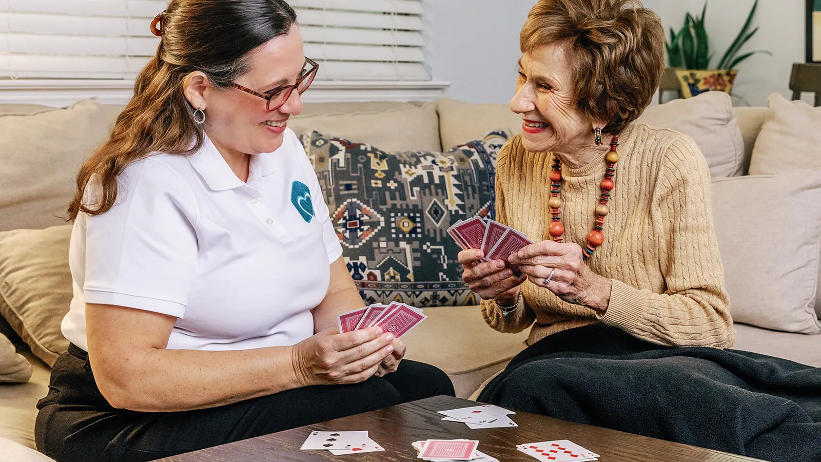 a couple of women playing cards on a couch