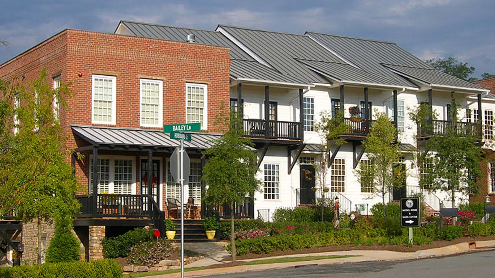 Row of modern townhouses in Woodstock with brick and white siding facades, balconies, and landscaped front yards on a sunny day.