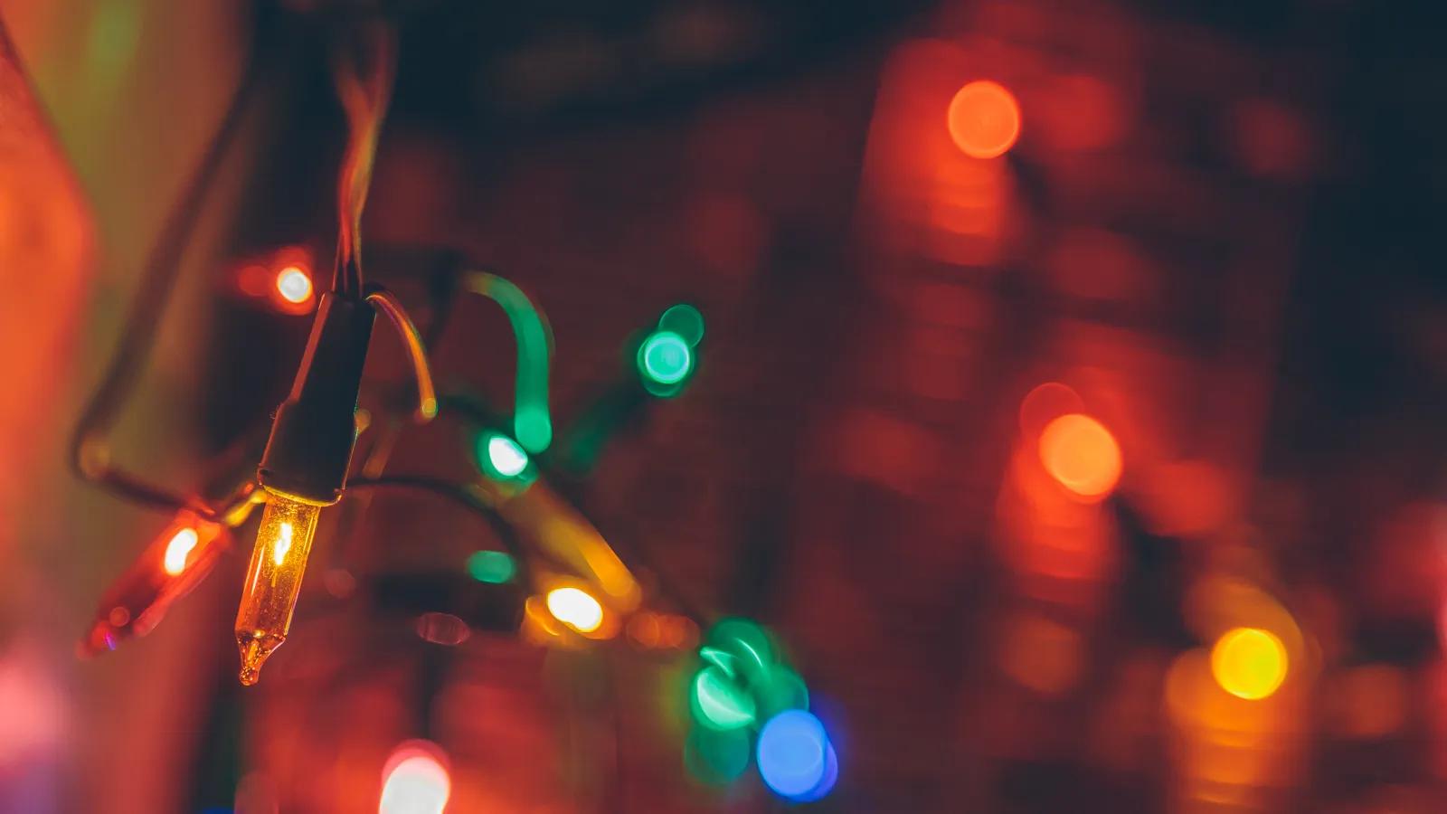 Close-up of colorful Christmas string lights glowing with red, green, yellow, and blue blurred background lights.