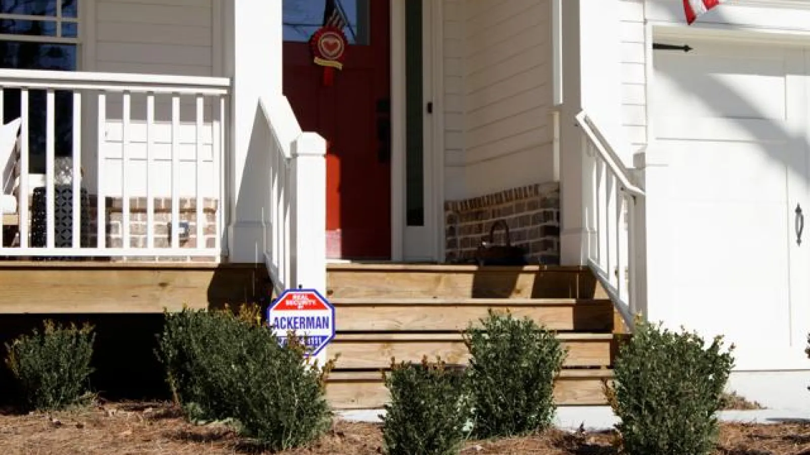 Front porch of a white house with Ackerman Security Protection sign