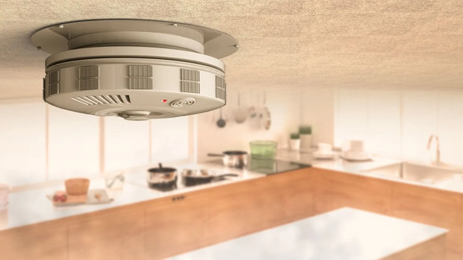 Smoke detector mounted on kitchen ceiling with modern kitchen appliances and counter below in soft lighting