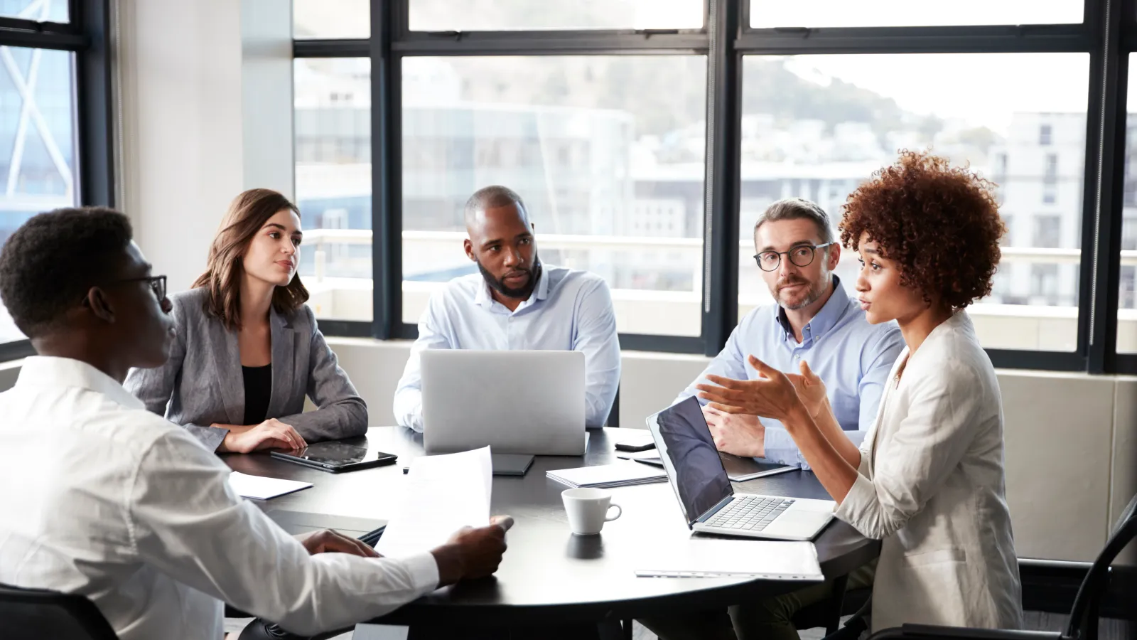 a group of people sitting around a table with laptops