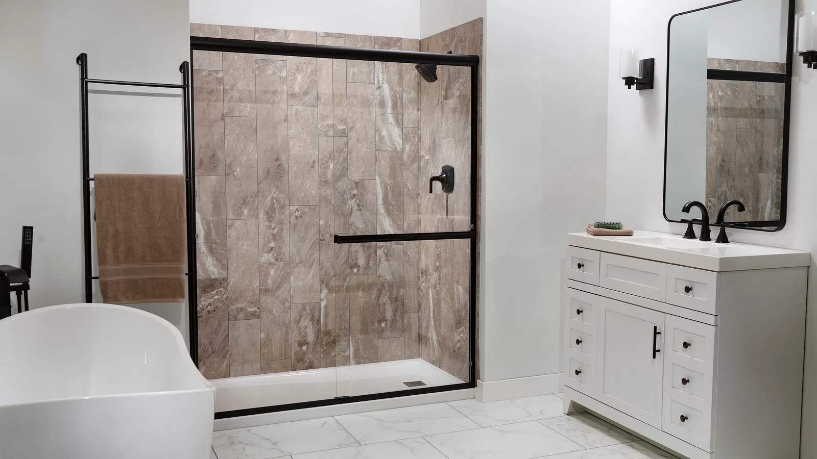 Modern bathroom with white freestanding tub, glass shower with brown tile, white vanity, and large mirror.