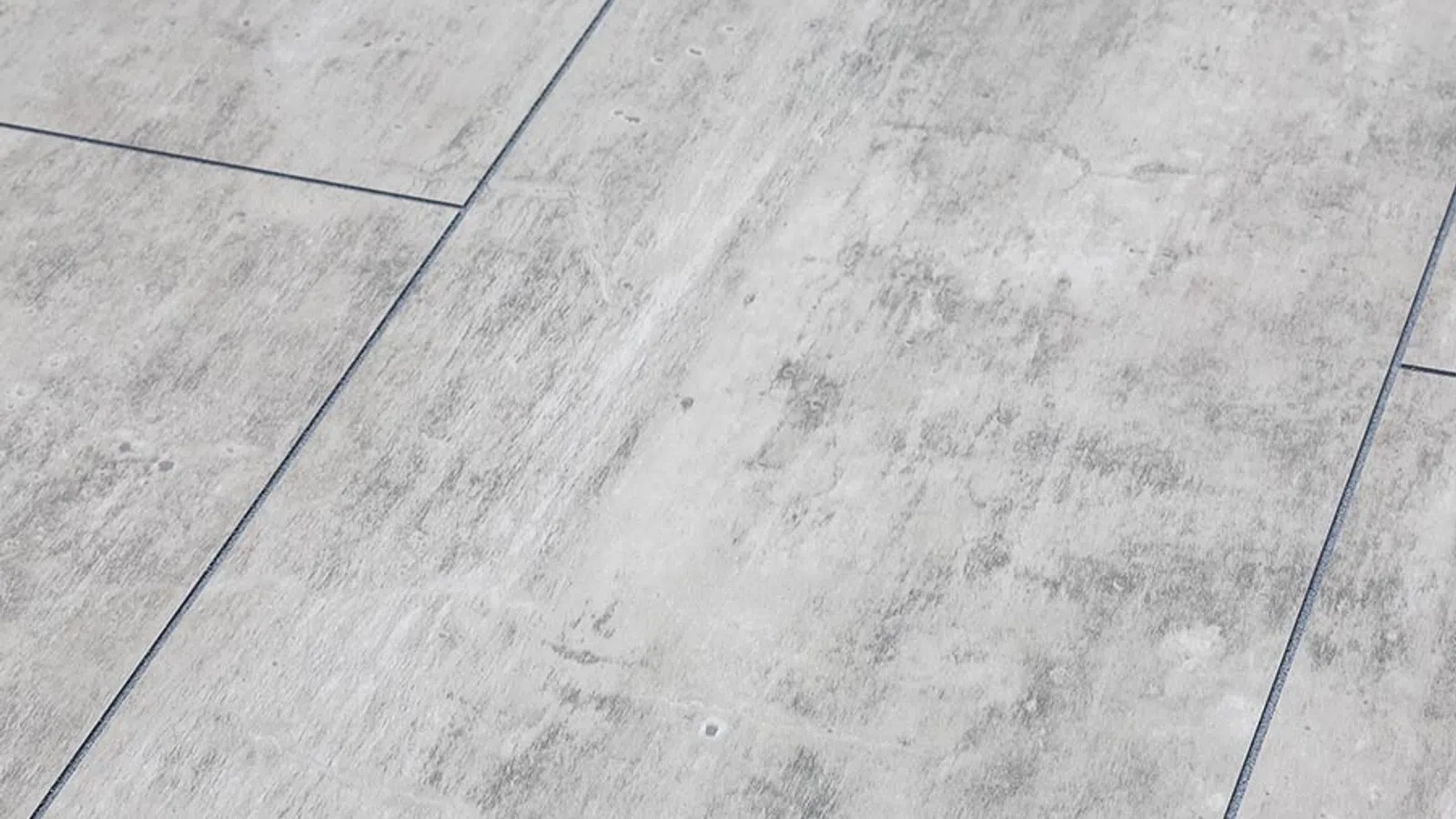 Close-up of light gray textured ceramic floor tiles with subtle veining and grout lines.