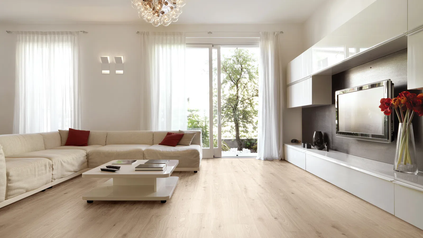 Modern living room with beige sectional sofa, wooden flooring, large window, and white cabinetry with a TV.