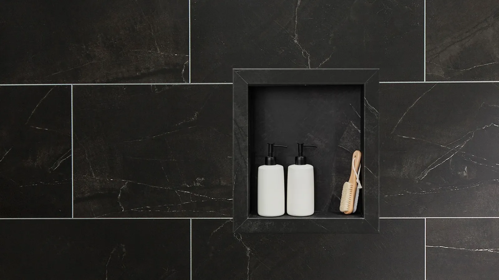Black tiled shower niche with two white pump bottles and a wooden brush inside for bathroom organization.