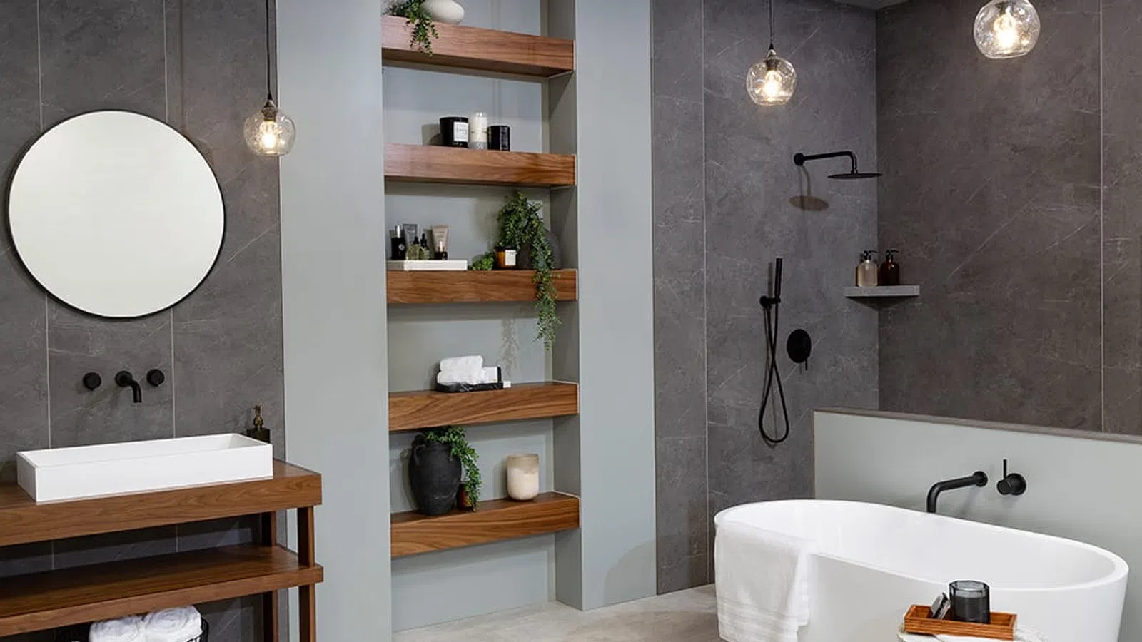 Modern bathroom with round mirror, white sink, freestanding bathtub, wooden shelves, and gray walls.
